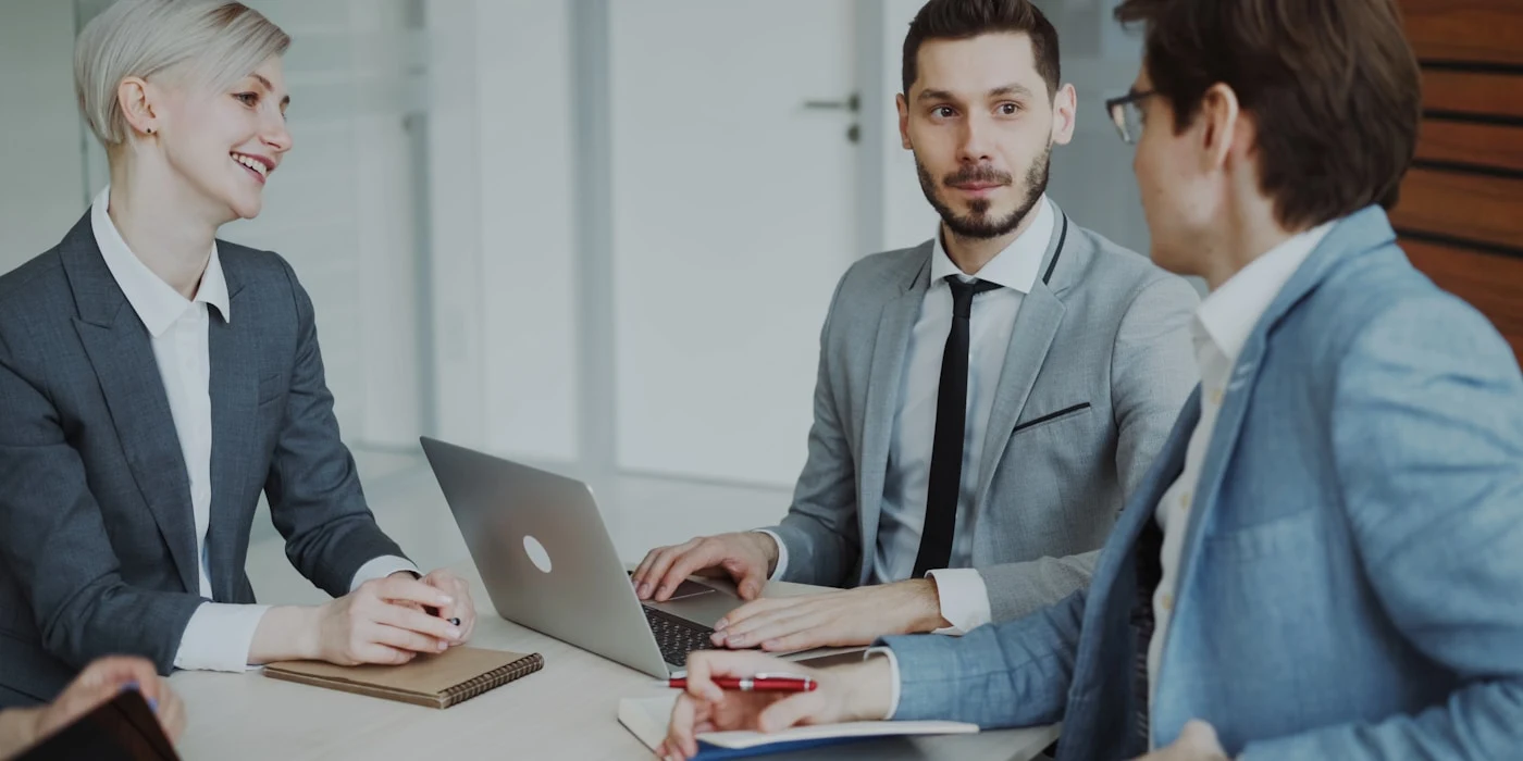 Business owners comparing SEO agency options during a consultation around a laptop